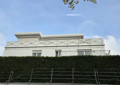 IBW Wuppertal: Moderner Gebäudedachabschluss mit auffälligem goldenen Geländerdetail vor blauem Himmel.